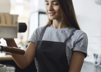 Nuori henkilö tekemässä kahvia kesätyöpaikassaan